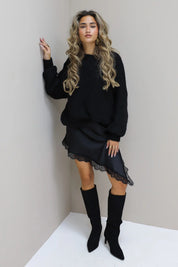 Model met zwarte cropped trui, kort rokje en hoge laarzen