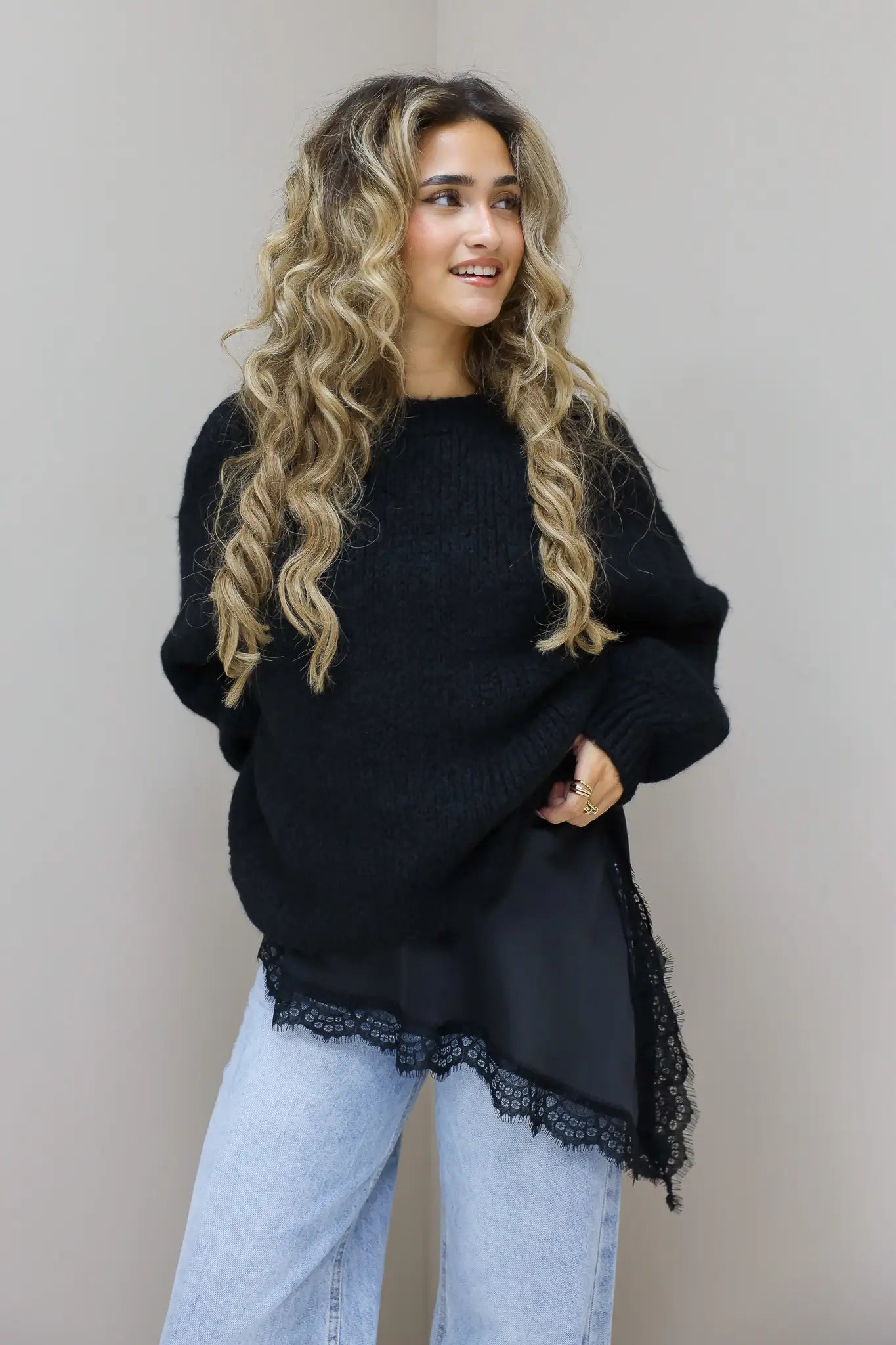 Model in zwarte cropped trui en bordeaux broek in studio