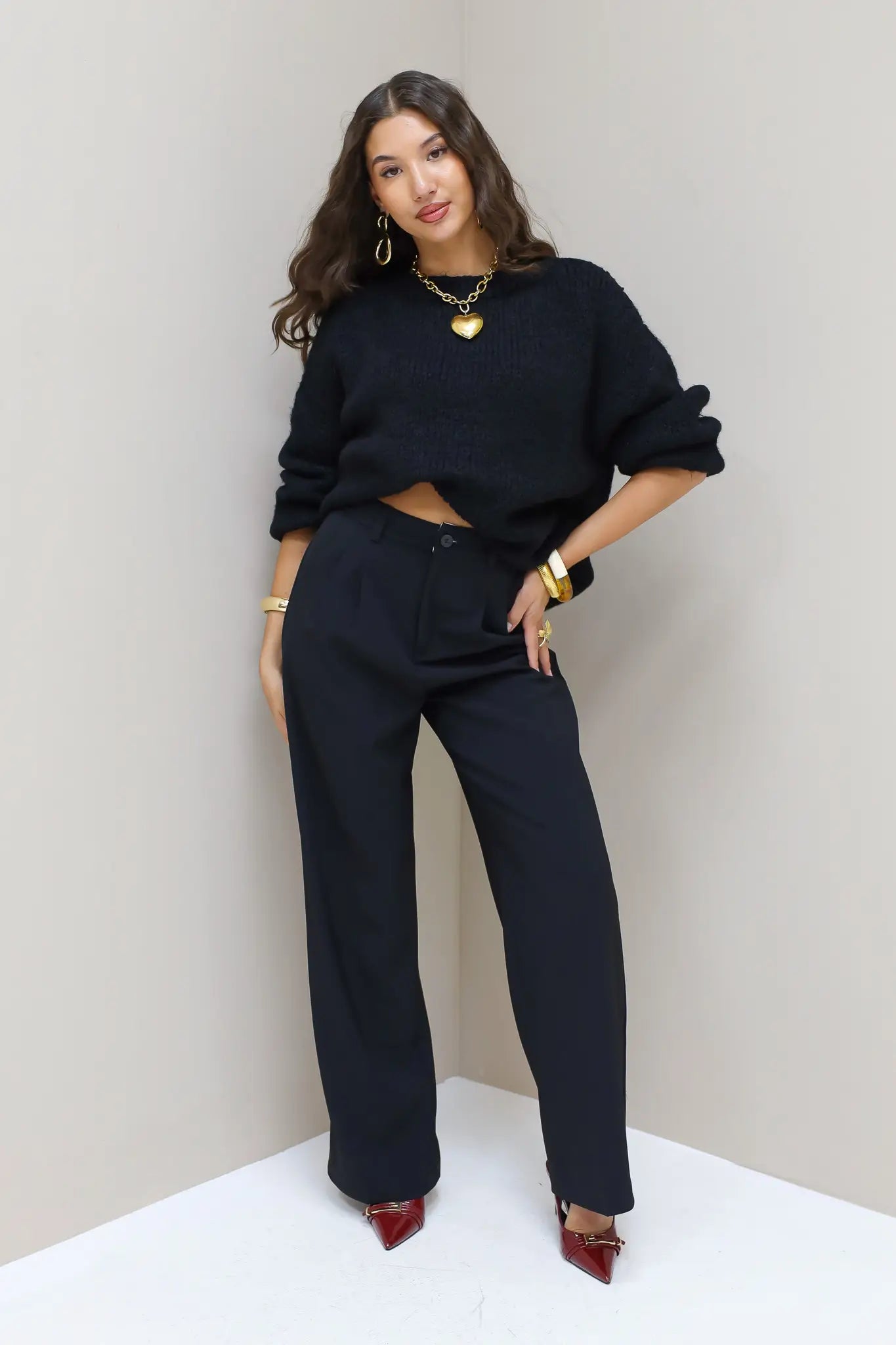 Model poseert recht in zwarte pantalon en zwarte trui