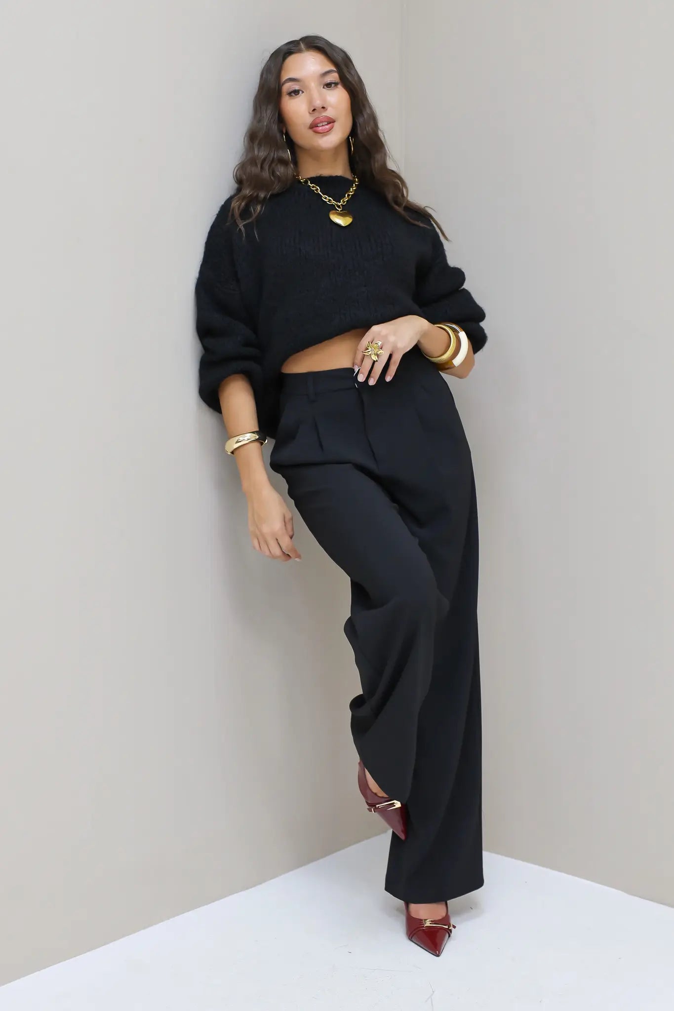 Model kijkt schuin met zwarte pantalon en zwarte trui