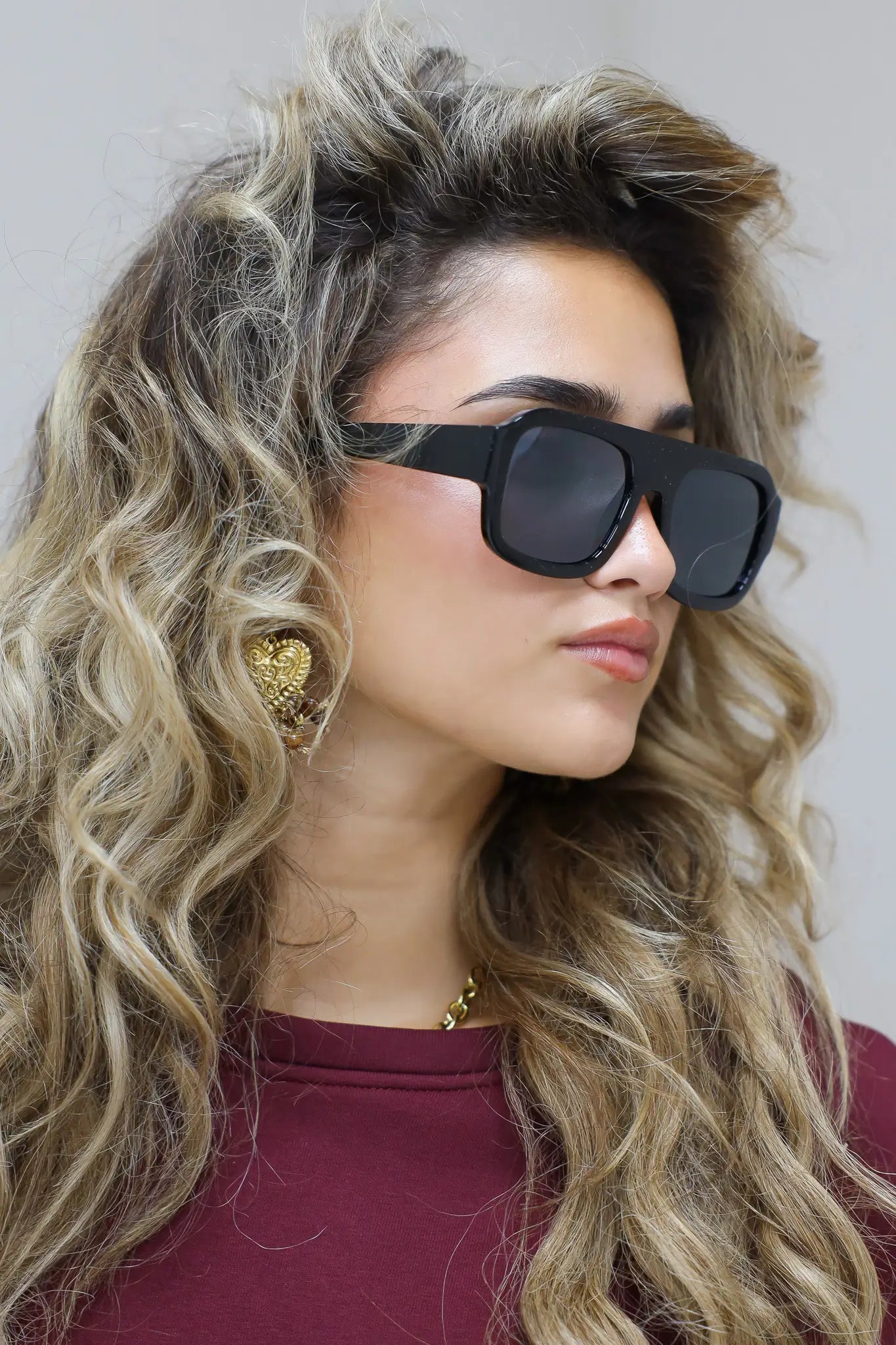 close-up van model met zwarte cat eye zonnebril en golvend haar in bordeaux top