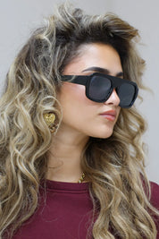 close-up van model met zwarte cat eye zonnebril en golvend haar in bordeaux top